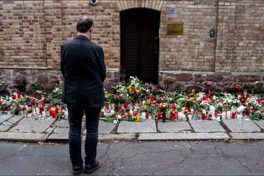 A mourner laying flowers outside the walls of the Halle synagogue, where you can see hundreds of bouquets left in memory of the victims of the attack, which initially targeted the synagogue and its worshippers.