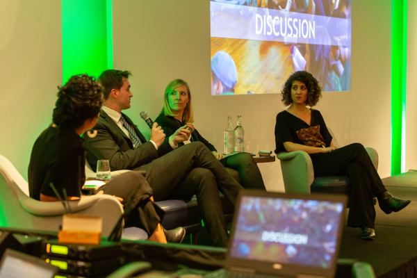 Charity staff from Solutions Not Sides and Seeds of Peace at a conference, speaking on stage about Israel-Palestine.